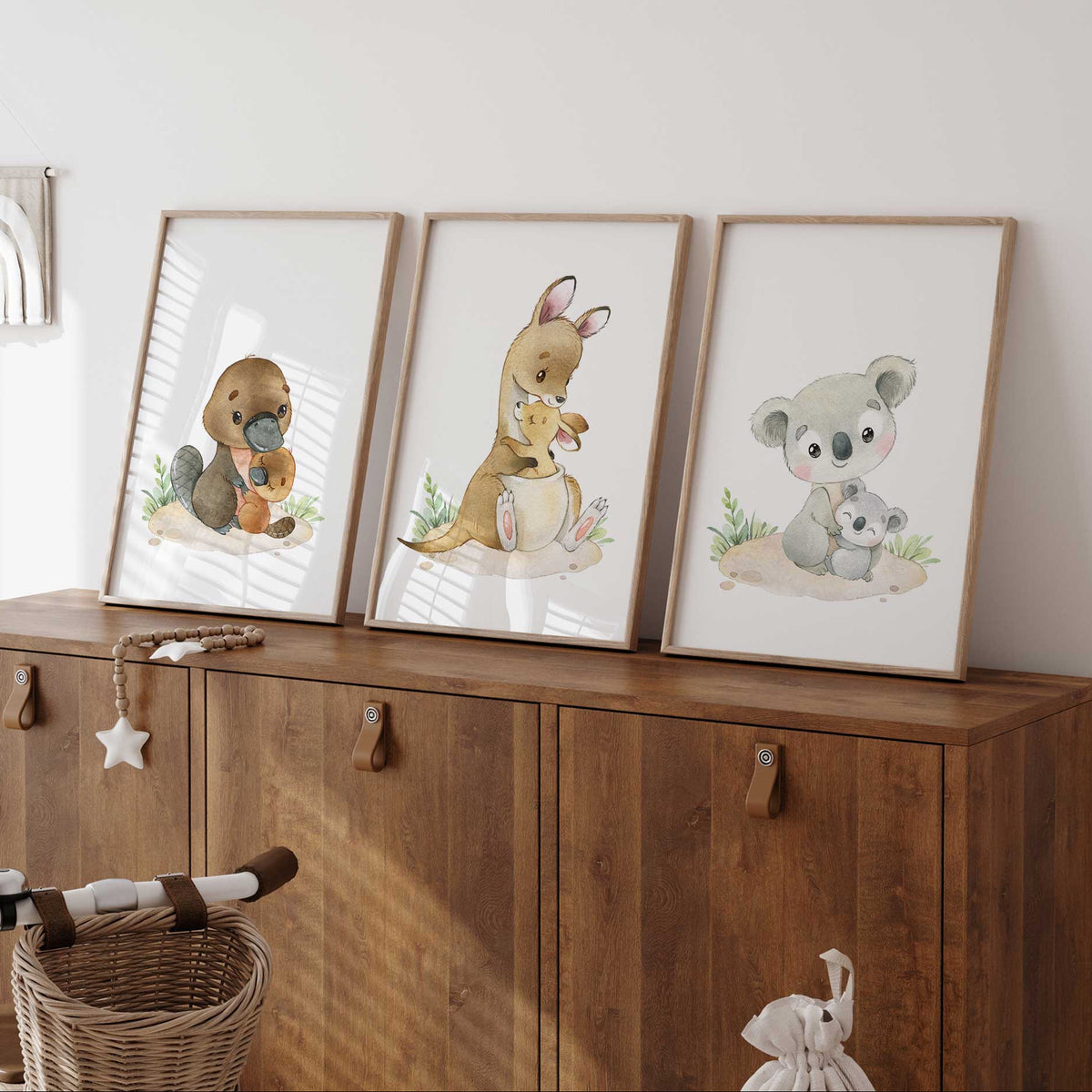 Three Australian mother and baby animal prints showing platypus, kangaroo and koala pairs with green foliage.