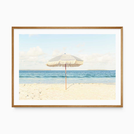 Beach umbrella wall art print featuring a neutral coastal scene with sand and ocean.