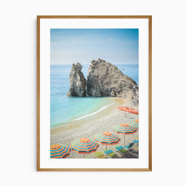 Coastal beach scene with umbrellas, sea, and rock formation