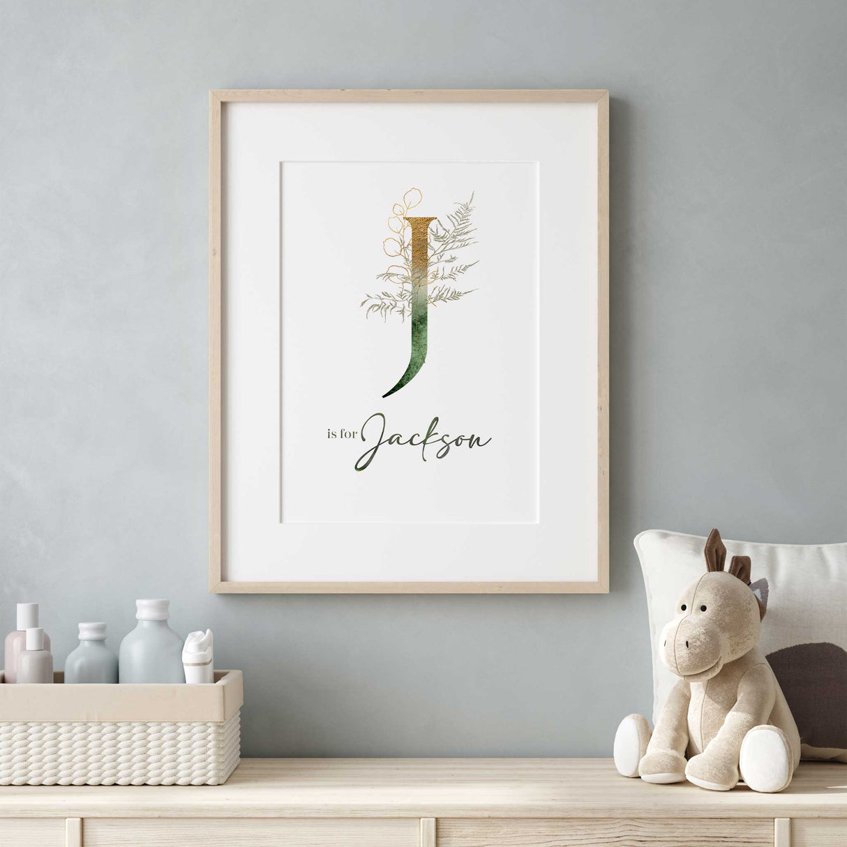 Eucalyptus nursery name print with large personalised initial, soft green leaves and elegant gold detailing.