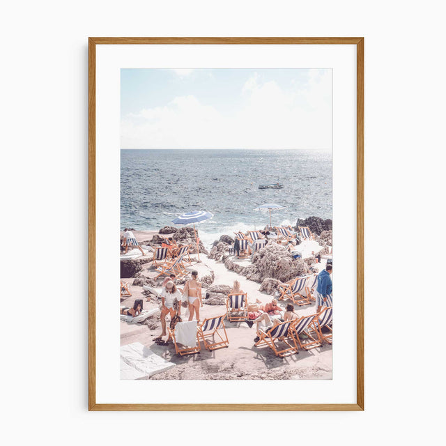 Coastal beach wall art with striped loungers on rocky Mediterranean shore