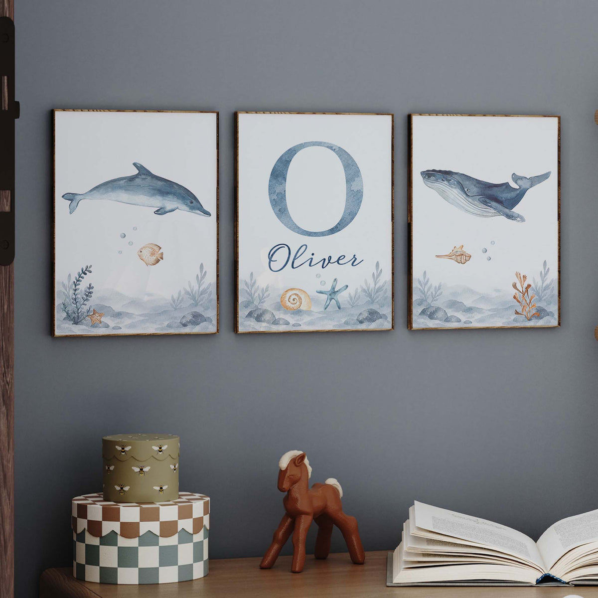 Ocean nursery prints featuring a blue dolphin, whale and personalised initial and name with shells and coral.