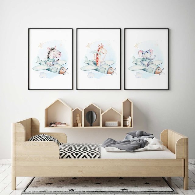 Set of three watercolour prints with zebra, giraffe and elephant pilots in mint aeroplanes, with clouds and stars on white.
