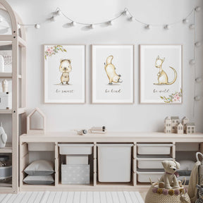A set of three animal prints featuring kangaroos, wombats, and platypuses in a nursery room setting with a white and pink colour scheme.
