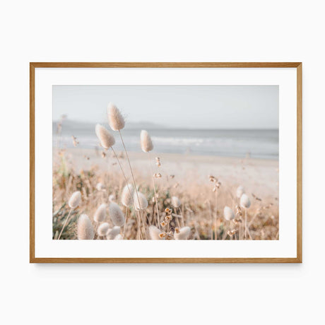 Beach grass coastal wall art featuring soft neutral reeds beside a calm blue ocean shoreline