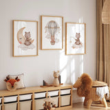 Bear nursery wall art set with three prints showing a bear on a moon, a hot air balloon, and a cloud with stars