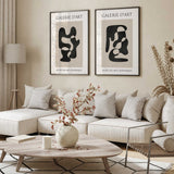 Set of two black and beige abstract prints with flowing organic shapes, cream margins and French gallery lettering.