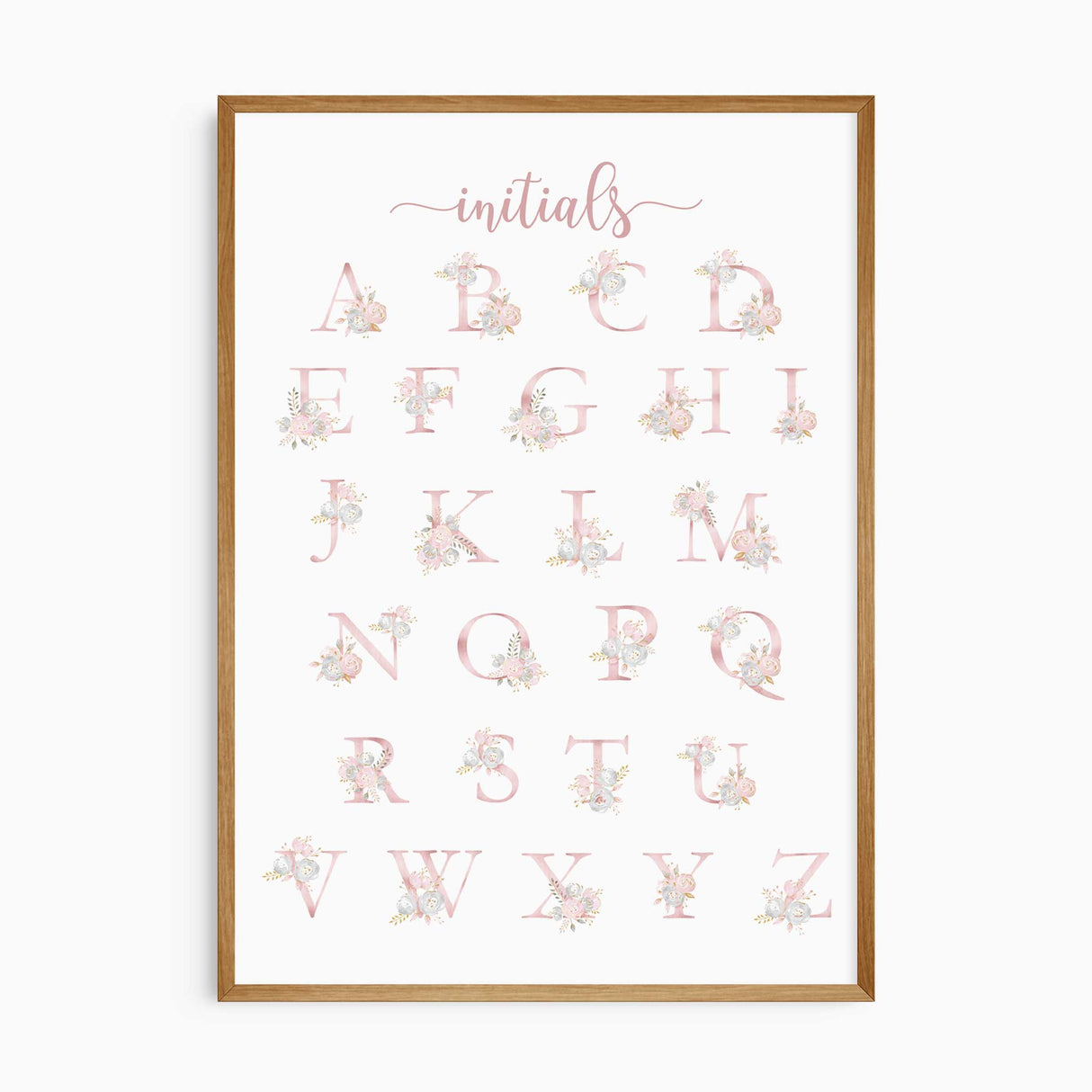 Close-up of a blush pink floral initial with soft pastel flowers, grey leaves and gold-style details.