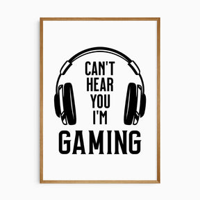 A black and white wall art with the phrase 'Can't hear you I'm gaming' and an illustration of headphones on a wooden frame.