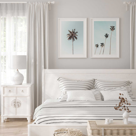 Set of two coastal palm tree wall art prints featuring sunlit palms against clear soft blue skies