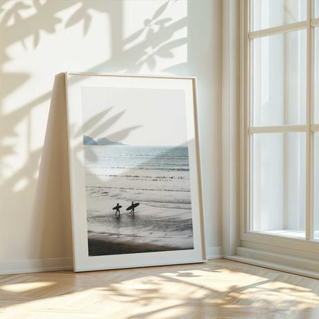 Surfer walking along the beach at sunrise with ocean waves