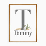Personalised dinosaur initial print with a large grey initial, and childs' name, a dinosaur egg and green fern details.