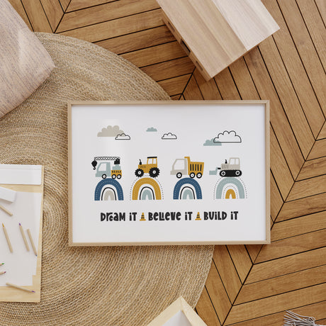 Dream It Believe It Build It print with four building vehicles on navy, mustard and aqua rainbows beneath clouds.