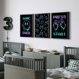 Set of three gaming prints featuring 'GAME OVER' text with a smiley face and lightning bolts, a pattern of game controllers and smiley faces, and 'PRESS START' text with a game controller.