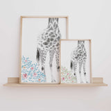 Girls nursery giraffe prints in pastel blue and sage floral styles displayed side by side to show both colour options for baby girl wall art.