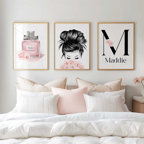 A framed print of a pink perfume bottle labeled "Parfum" with a black bow on top, surrounded by pink flowers.