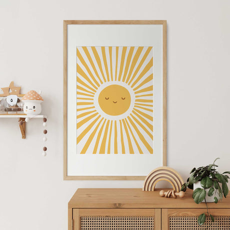 Happy sun wall art with a golden yellow circular face, closed eyes and radiating sunburst rays without lettering.