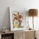 Whimsical Wild One Giraffe Print featuring a bespectacled giraffe with a bowtie, surrounded by lush green botanical elements, perfect for kids' rooms.