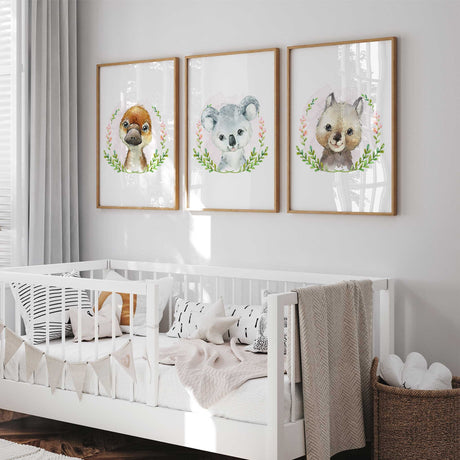 Three Australian animal portraits featuring a koala, platypus and wombat surrounded by green leaves and pink blossoms.