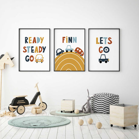 Car wall art set with personalised name on a mustard road print, flanked by Ready Steady Go and Let's Go designs with cars.