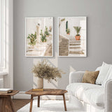 Mediterranean stone steps wall art print featuring whitewashed alleyway with potted plants and warm neutral coastal tones