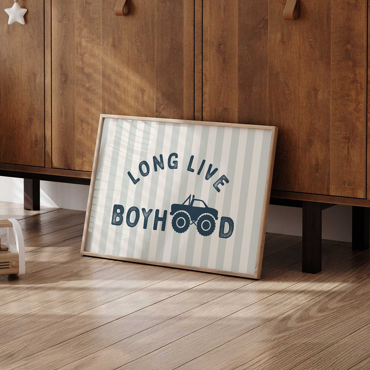 Long Live Boyhood monster truck design with navy text, oversized wheels and a pale sage and cream striped background.