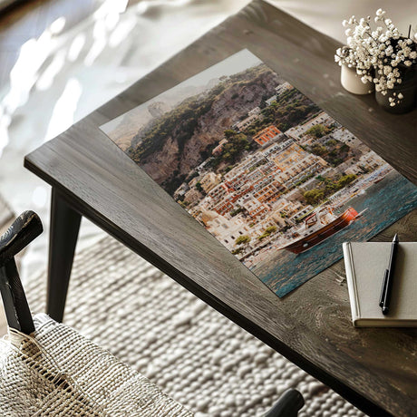 Positano Italy photography print featuring a wooden boat on blue water below the colourful cliffside town