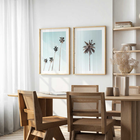 Minimalist palm tree wall art set featuring one single palm against a soft blue sky and a second print with four tall palms, perfect for coastal or boho decor.