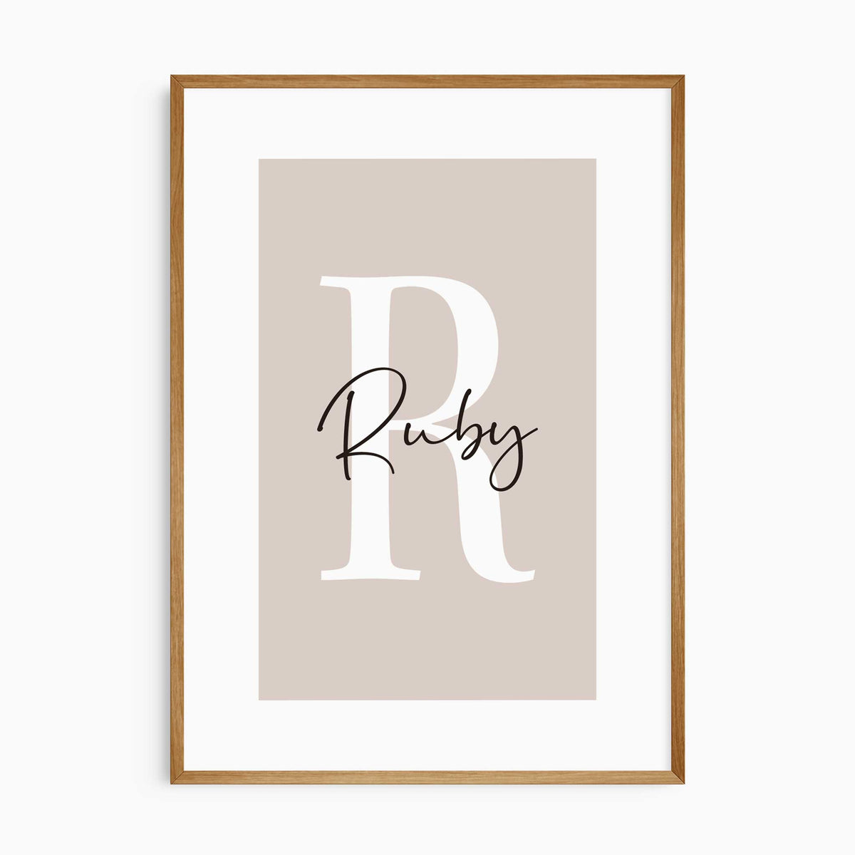 Personalised name print with a large white initial and black script lettering on a warm pink background.