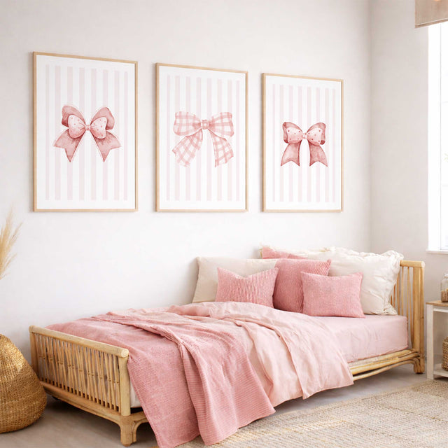 Pink bow wall art set of three with patterned ribbon illustrations, pale pink striped backgrounds and white borders.