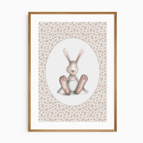 Seated grey-brown bunny with pink ears and paws inside a white oval, surrounded by a pink rose and green leaf pattern.