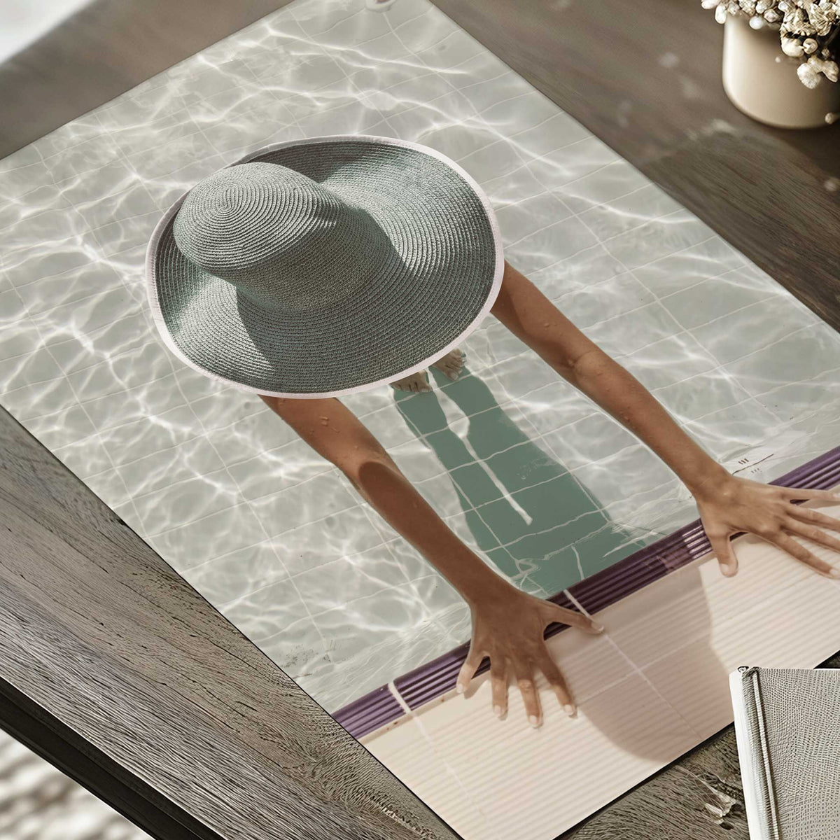 Poolside photography print showing a woman in a woven sunhat, with sunlight reflecting across pale swimming pool water.