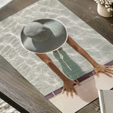 Poolside photography print showing a woman in a woven sunhat, with sunlight reflecting across pale swimming pool water.