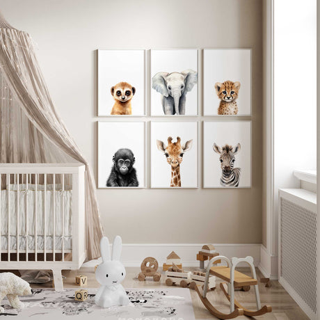 Set of six neutral safari animal nursery wall art prints featuring baby elephant, giraffe, zebra, cheetah, gorilla and meerkat displayed as a gallery wall in a modern baby nursery with cot and wooden toys, designed for gender neutral baby room decor