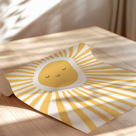Close view of a smiling golden yellow sun print with closed eyes, a small curved mouth and long rays on a light background.
