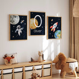 Space nursery wall art set with astronaut rocket and personalised initial print for boys room decor.