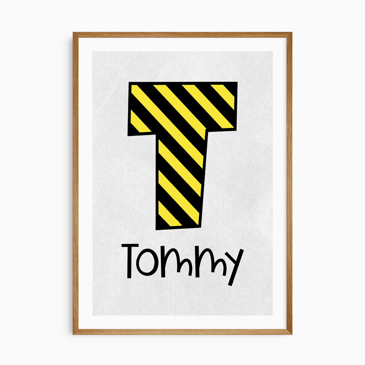 Personalised construction name print with a yellow and black striped initial above kids name on light grey with a white border.