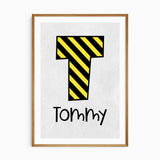 Personalised construction name print with a yellow and black striped initial above kids name on light grey with a white border.