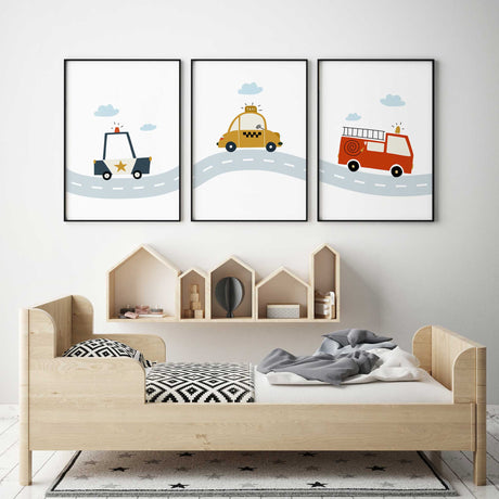 Set of three vehicle wall art prints with a police car, yellow taxi and red fire engine on a pale blue road.