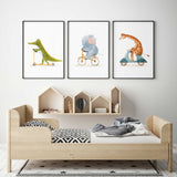 Watercolour animal wall art set of three with a crocodile and giraffe riding scooters and an elephant riding a bicycle.