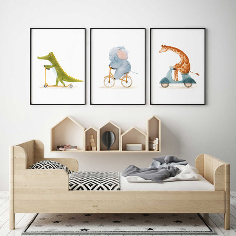 Watercolour animal wall art set of three with a crocodile and giraffe riding scooters and an elephant riding a bicycle.